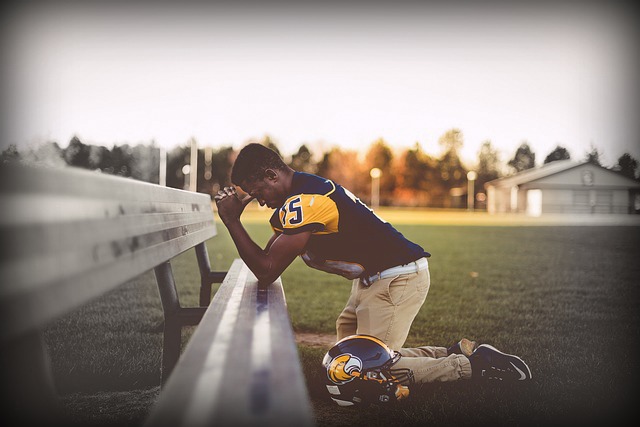 Football player kneeling in prayer